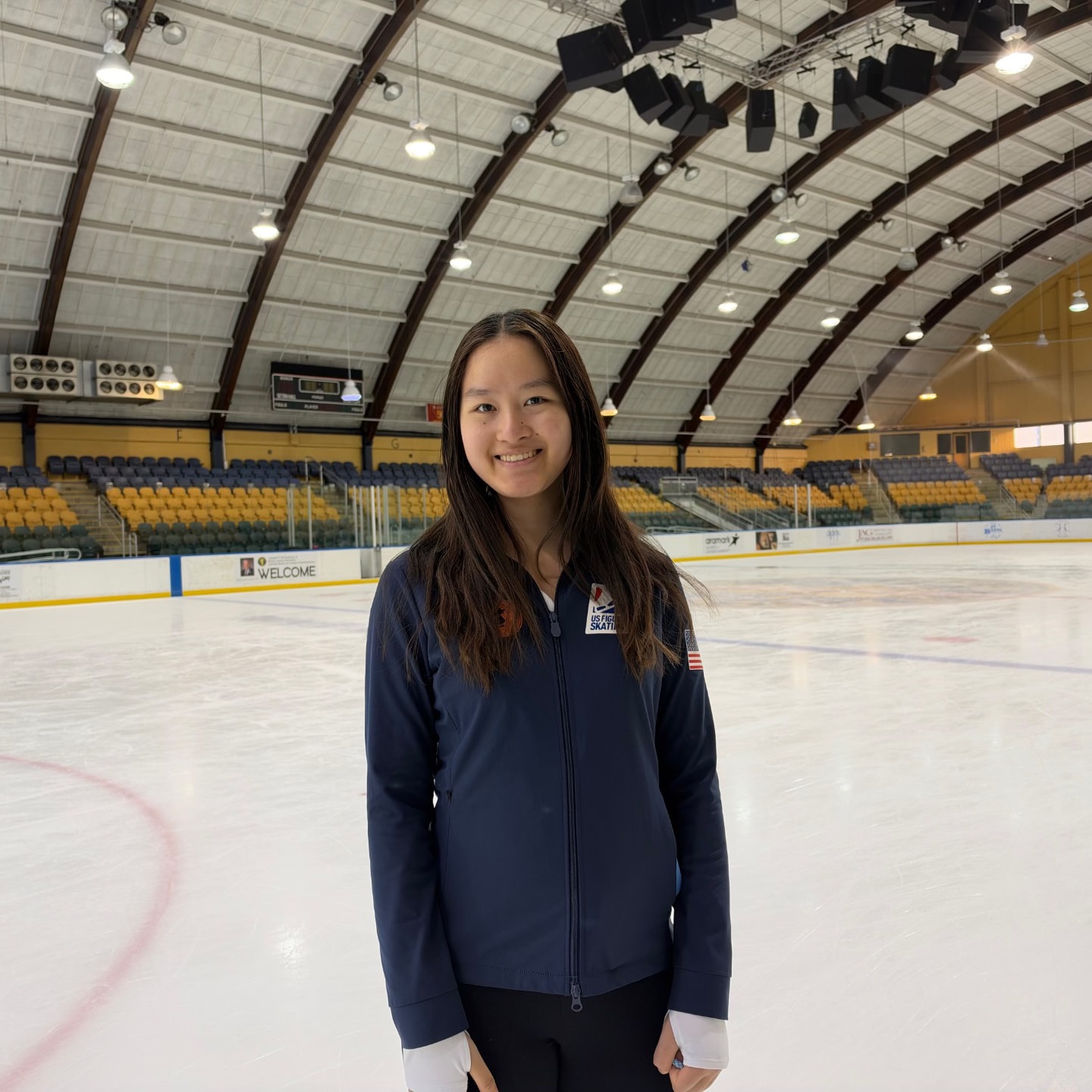 Audrey Hong, founder of SkaterSense, smiling on the ice in her US Figure Skating jacket